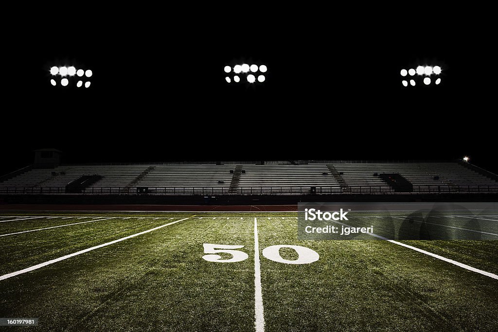 Fifty-yard line of football field at night American football field at night under the stadium lights. American Football Field Stock Photo