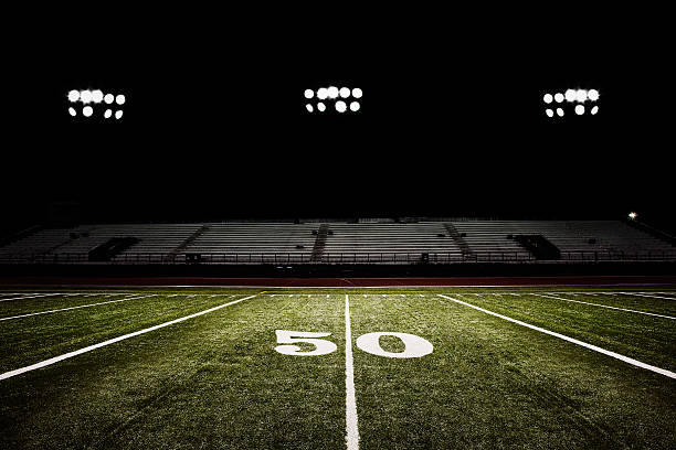 Fifty-yard line of football field at night American football field at night under the stadium lights. turf photos stock pictures, royalty-free photos & images
