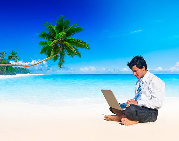 istock Businessman sitting barefoot on a beach using a laptop 160198040