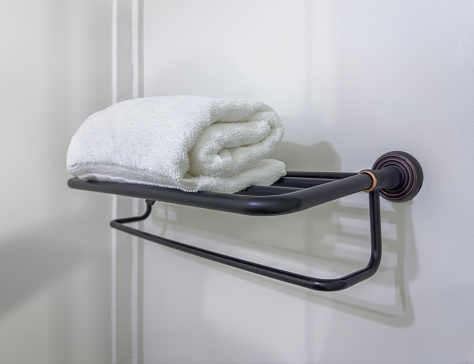 Rolled clean white towel on a copper decorative shelf