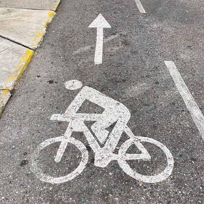 Cyclist symbol on the floor painted in white color a little worn on the asphalt in the street of Caracas