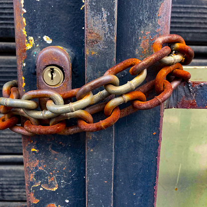 Close up view of rusty chain securing a gate of metal bars in the street of Caracas city