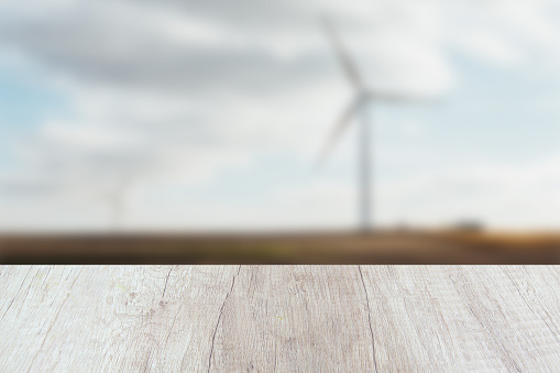 Empty white and rustic wooden table with a defocused windmills fields background