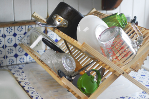 An assortment of dishes drying on an old-fashioned dish drainer.