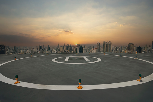 Symbol for landing a helicopter on the rooftop.Heli Copter parking lot on the deck with sunset in the capital of Thailand. Space for helicopter landing on high-rise buildings.