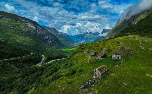 istock Scenic landscape featuring a mountain range with lush green grass and small cottages 1602313993