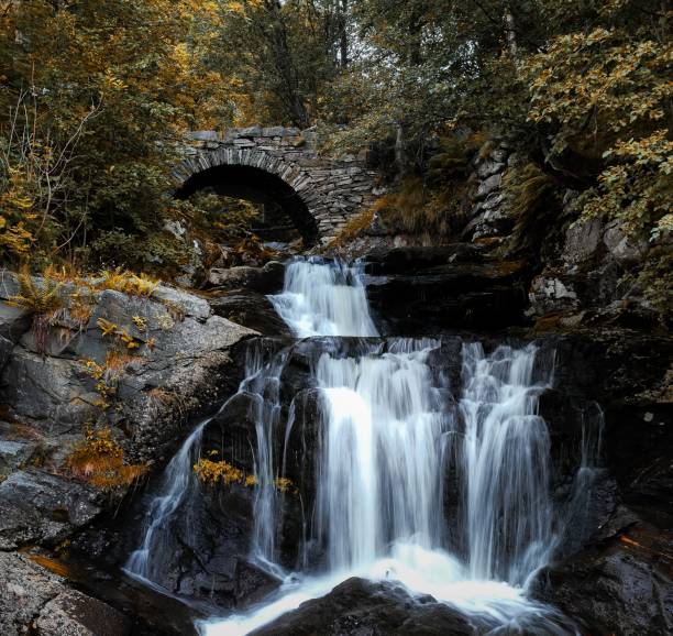 istock Stunning view of a waterfall cascading down rocks under a bridge 1602313999
