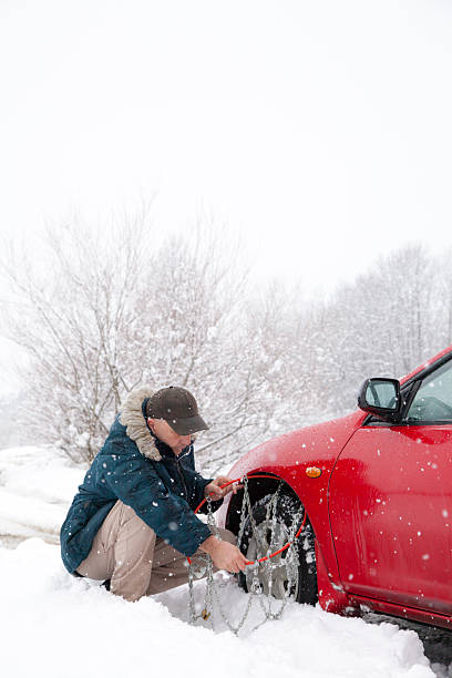 istock Mid aged male driver mounting car tyre chains 160234497