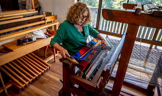 Mature woman at work weaving on her loom