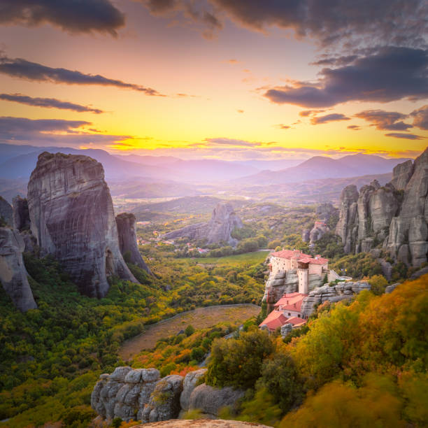 istock Meteora, Greece at romantic sundown time with real sun and sunset sky. Meteora - incredible sandstone rock formations.  The Meteora area is on UNESCO World Heritage. 1602394861
