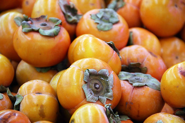 Heap of Brightly Colored Persimmon Fruit stock photo