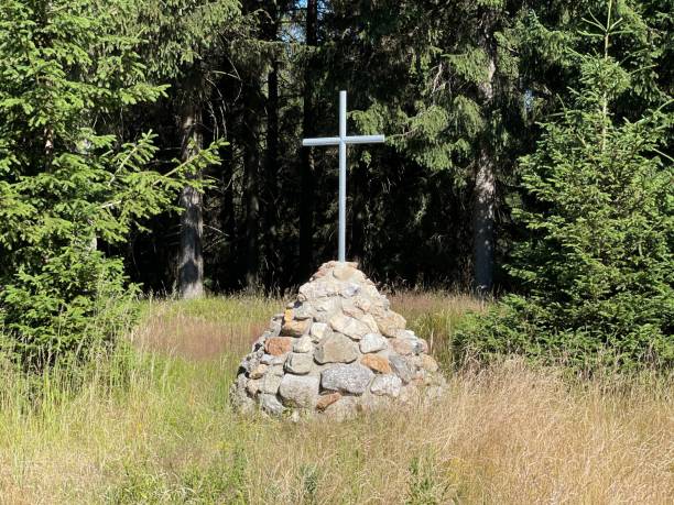 istock Cross on a small rocky hill in a grassy field 1602480131