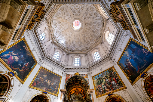 The beautiful interior of the church of Santa Maria della Pace (Church of Saint Mary of Peace) in the historic heart of Rome, in the Piazza Navona district. Built in 1482 during the pontificate of Sisto IV, the church was designed in the Renaissance style with a trapezoidal plan and an octagonal cross by the architect Baccio Pontelli. In 1656 Pietro da Cortona designed the Baroque-style façade with a semi-circular colonnade. Inside the church, rich in numerous chapels, there are architectural and pictorial works by Raphael, Antonio da Sangallo, Rosso Fiorentino, Baldassarre Peruzzi and Orazio Gentileschi. In 1980 the historic center of Rome was declared a World Heritage Site by Unesco. Super wide angle image in 16:9 ratio and high definition quality.