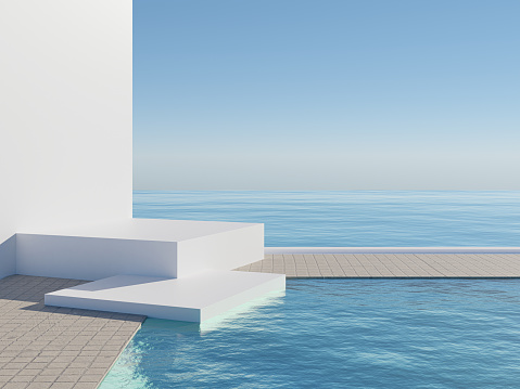 Man sits on edge of infinity pool looking out over view of Santorini caldera, Greece