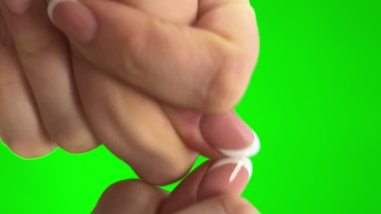 on a green background chromakey, woman shows two hands clashes with thumbs then removes her hands shows a fig by folding it from the fingers of his hand. Shooting a hand in the form of a fig close-up