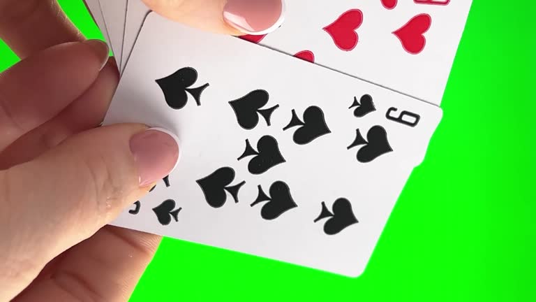 Hand holding four Nines on a green background close-up female hands with french manicure. woman sorts through cards, examines them folds and spreads out like fan four cards left of same suit