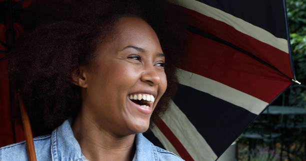 istock Smiling young woman with a union jack umbrella 1602535246