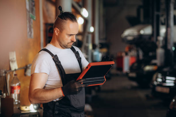 istock Male mechanic with tablet computer in car service center 1602546439