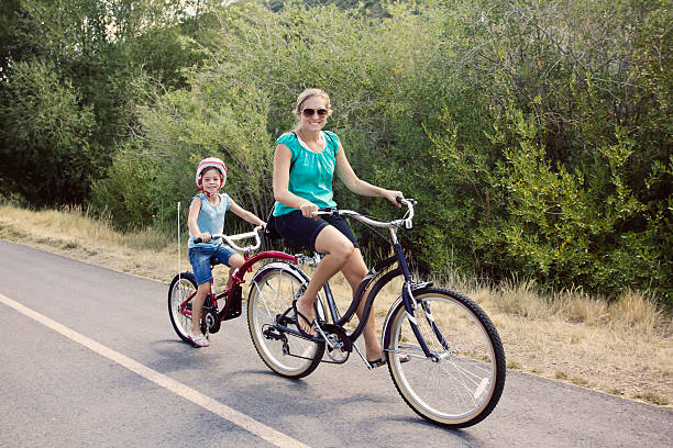 A mother and daughter enjoying a tandem bicycle ride together on a bike path