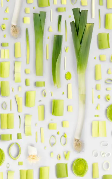 Abstract background made of Leek vegetable pieces, slices and leaves isolated on gray background.