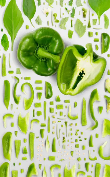 Abstract background made of Green Pepper vegetable pieces, slices and leaves isolated on gray background.