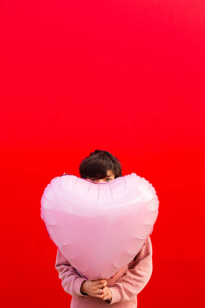 istock Boy holding a big red heart shaped balloon 1602562320