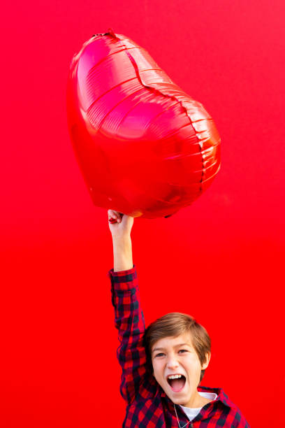 istock Boy holding a big red heart shaped balloon 1602562321