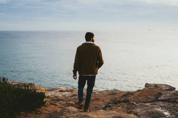istock Young Man walking on a cliff by the sea 1602578017