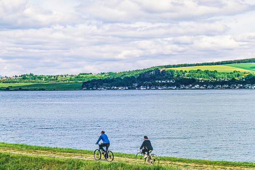 Inverness, United Kingdom-May, 2020: Couple cycling on a seaside path in Scotland