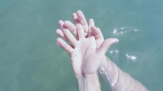 joined and intertwined hands of a couple in love. the skin is wrinkled and wet from bathing in sea water. bonding and friendship concept.holding hand.