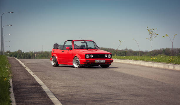 volkswagen golf cabriolet rossa su una strada rurale - vintage toning foto e immagini stock