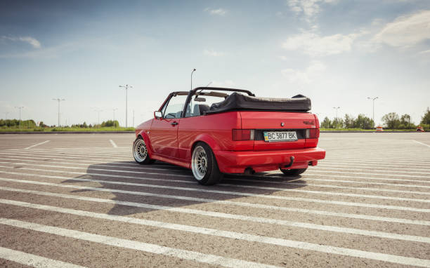 volkswagen golf cabriolet rossa su un grande parcheggio - vintage toning foto e immagini stock