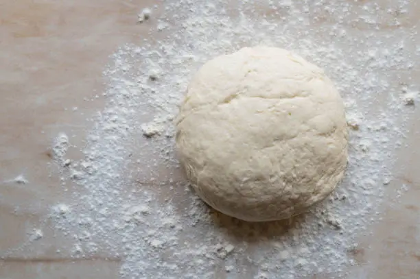 Homemade fresh rised yeast dough with flour on kitchen counter background from above with copy space