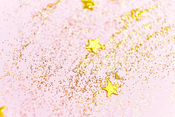 istock Golden glitter sequins and stars on a pink background. 1602707620