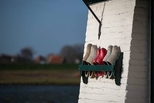 Row of wooden shoes on a rack at a wall of a windmill.