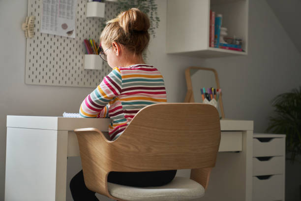 istock Back view of elementary age girl studying at the desk 1602713944