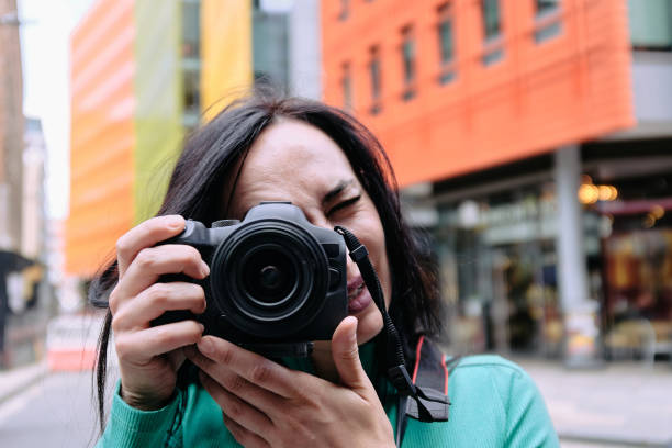 une jeune femme blanche capture la scène de la ville à travers un appareil photo sans miroir - looking at camera one person urban scene photography photos et images de collection