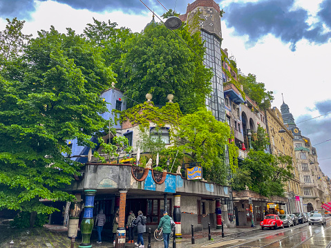 Hundertwasser house in Vienna, Austria during a rainy day in spring with tourists walking the streets.
