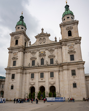 Salzburg Cathedral (Salzburger Dom) i in the Old Town of Salzburg, Austria during an overcast springtime day with tourist walking on the square.