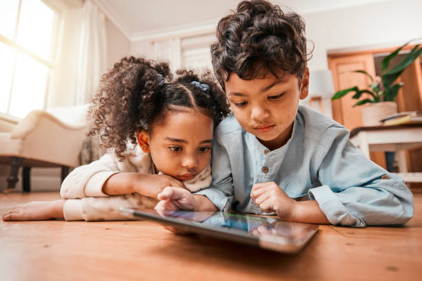 istock Children, tablet and home education, online development and internet games for kindergarten or home school. Young kids relax on floor with digital technology for video or app streaming subscription 1602852365