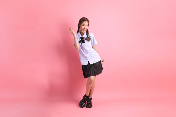 The Asian girl in Thai student uniform standing on the pink background.