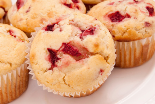 Close-up of homemade jumbo sized strawberry muffins that are in the paper baking liners. These muffins were made with buttermilk and frozen strawberries. Shot in natural day light. Selective focus with shallow definition of field. 