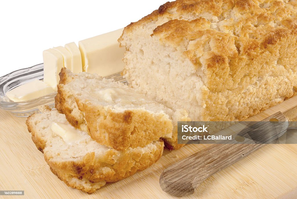 loaf of sliced beer bread on a cutting board homemade loaf of sliced beer bread served with butter and an old knife lying on the cutting board. The background is white.  Baked Stock Photo