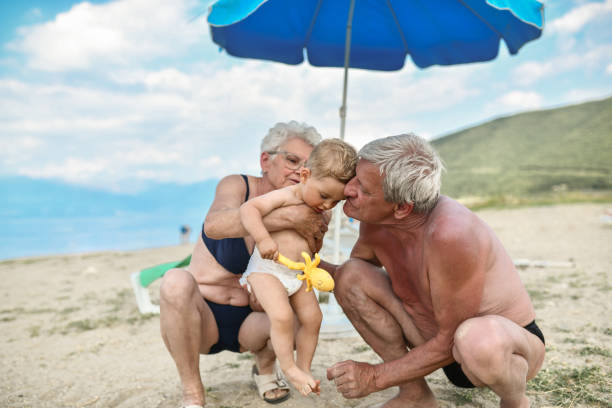 밖에서 아기에게 해변의 즐거운 분위기를 보여주는 돌보는 조부모 - grandson water waterfront portrait 뉴스 사진 이미지