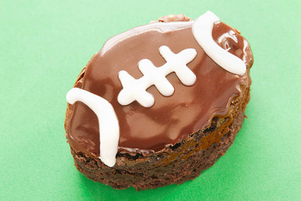 brownie al cioccolato e decorate come un a forma di calcio sfondo verde - foto stock