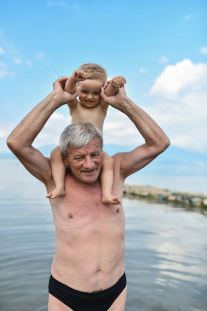 할아버지의 귀여운 아기를 위해 호수에서 피기백 어깨 타기 - grandson water waterfront portrait 뉴스 사진 이미지