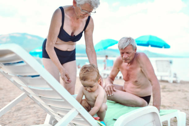 해변에서 아기 손자와 함께 시간을 보내는 돌보는 조부모 - grandson water waterfront portrait 뉴스 사진 이미지