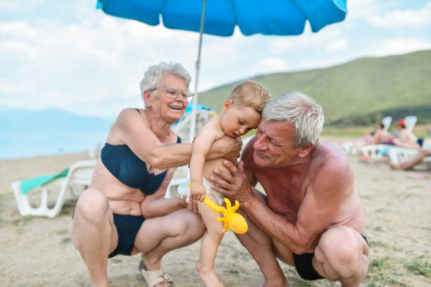 해변에서 아기와 놀고 있는 조부모 - grandson water waterfront portrait 뉴스 사진 이미지