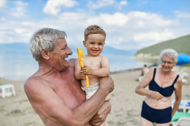 아기를 데리고 휴가를 가는 웃는 조부모 - grandson water waterfront portrait 뉴스 사진 이미지