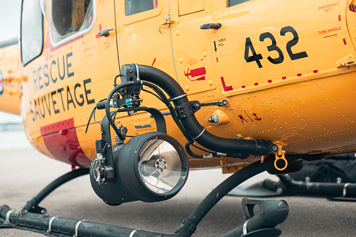 A Jet Ranger CH-139 helicopter belonging to the Royal Canadian Airforce Search and Rescue unit sits parked at the Collingwood Regional Airport in August of 2023. The photograph is focused on the search light on the right side of the helicopter.